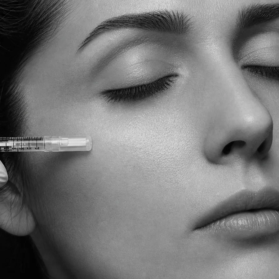 A fine syringe held with precision beside the cheekbone